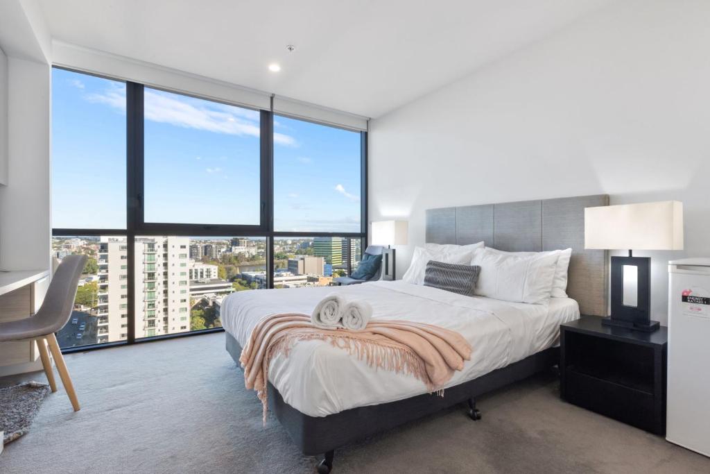 a bedroom with a large bed and large windows at Hearty Milton Apartments in Brisbane