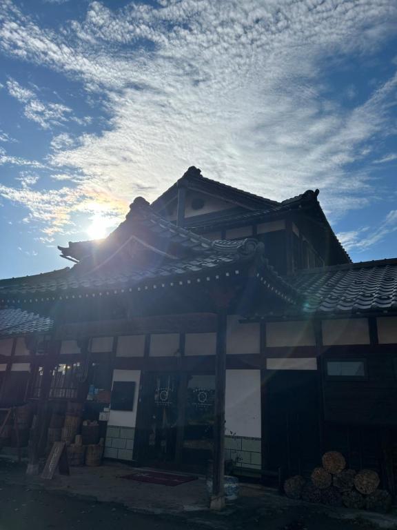 un bâtiment avec le soleil dans le ciel dans l'établissement 古民家ゲストハウス ナマケモノ, à Ōno