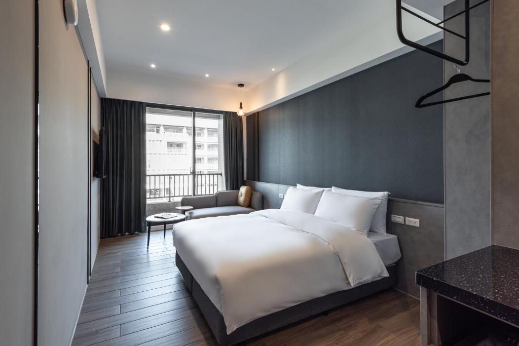 1 dormitorio con 1 cama blanca grande y 1 sofá en Hotel Euphemia en Taichung