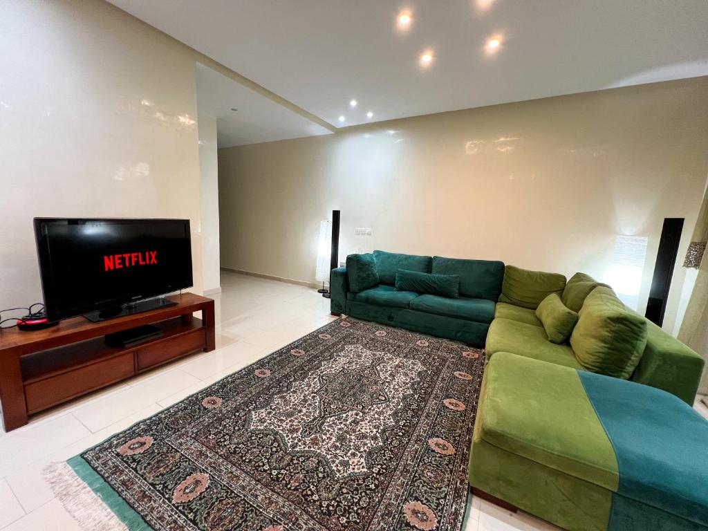 uma sala de estar com um sofá verde e uma televisão em Cozy & Confort au cœur de Kenitra em Kenitra