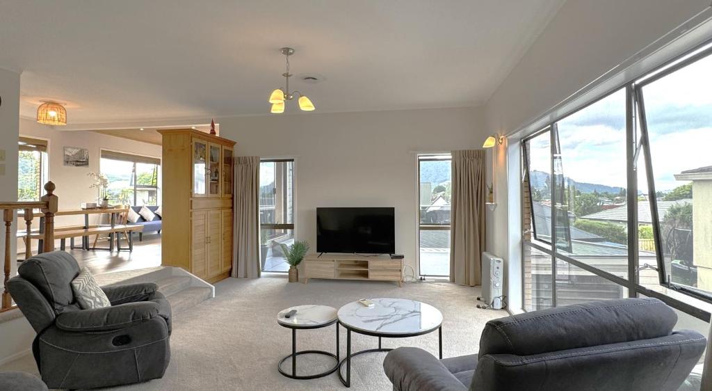 een woonkamer met 2 banken en een televisie bij Spacious retreat with Mountain View in Rotorua