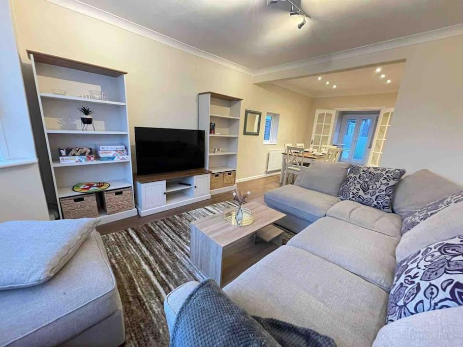 a living room with a couch and a flat screen tv at Cosy House near Harry Potter Studios in Leavesden Green