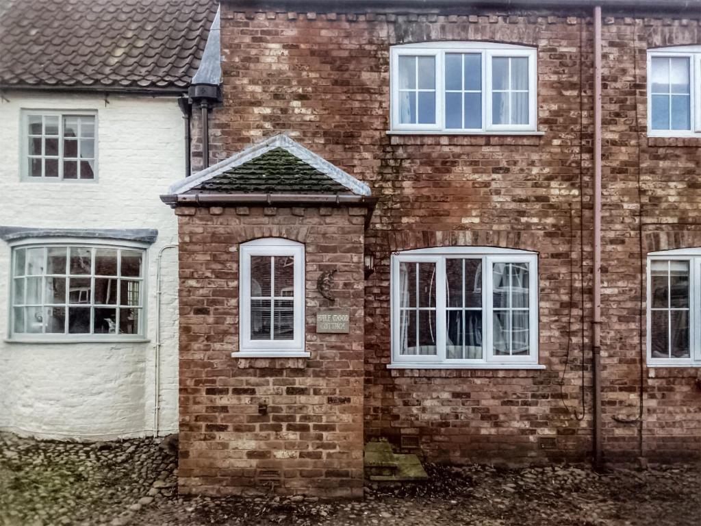 a brick house with three windows and a white at Half Moon Cottage in Brafferton