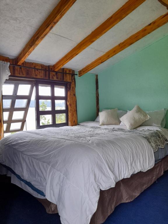 a bedroom with a large bed with white sheets at Cabañas atardeceres. in Valdivia