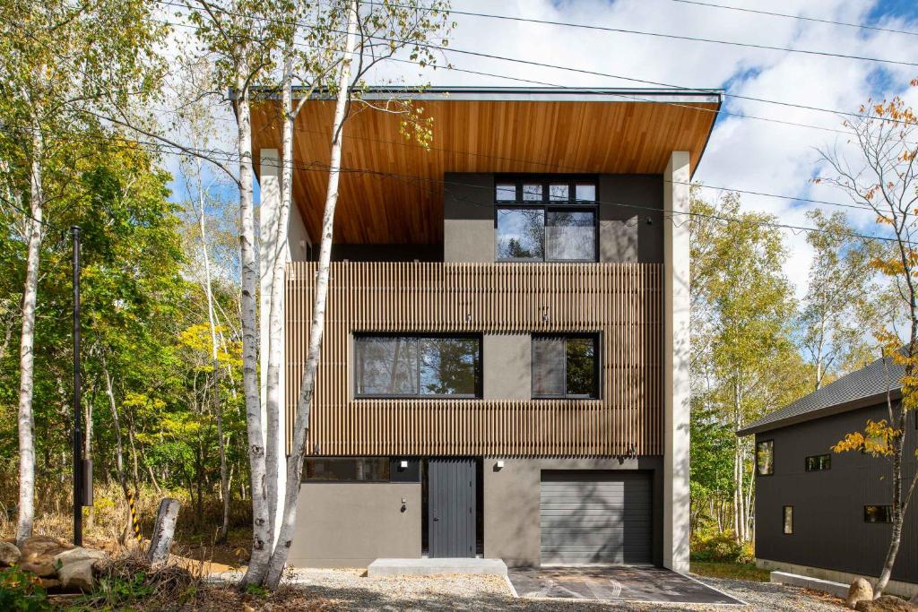 una casa en el bosque con una fachada de madera en Yuzen, en Kutchan