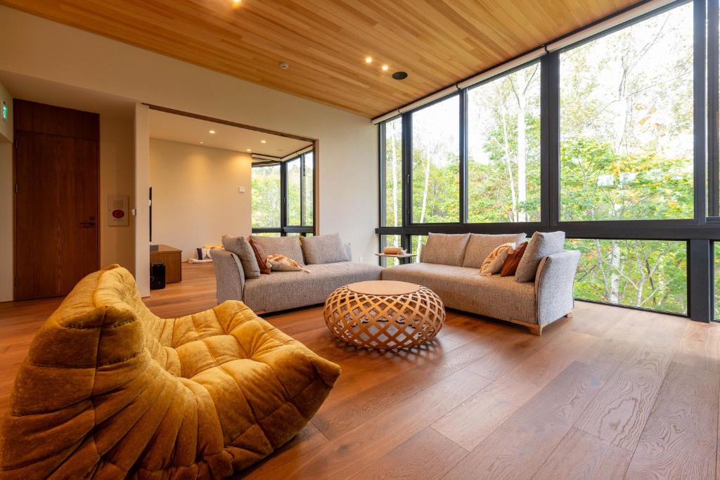 a living room with two couches and a large window at Yuzen 悠然 in Kutchan