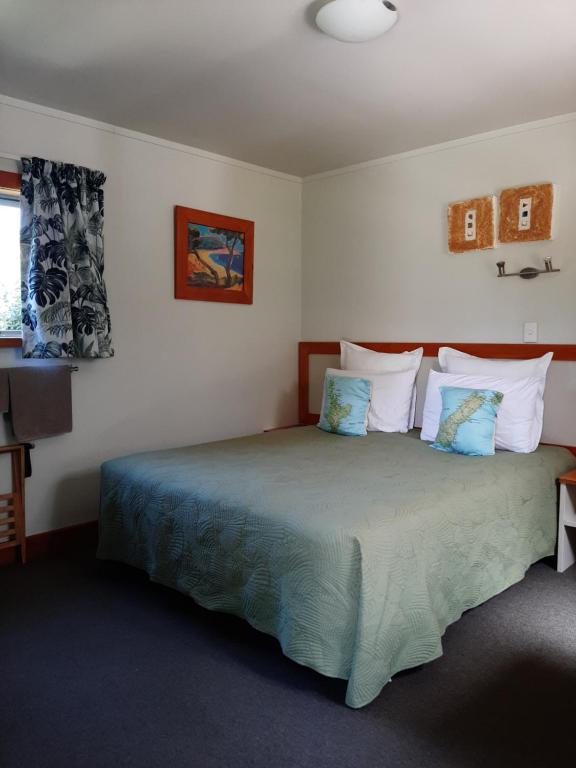 a bedroom with a bed with blue and white pillows at Eden's Edge Lodge in Motueka