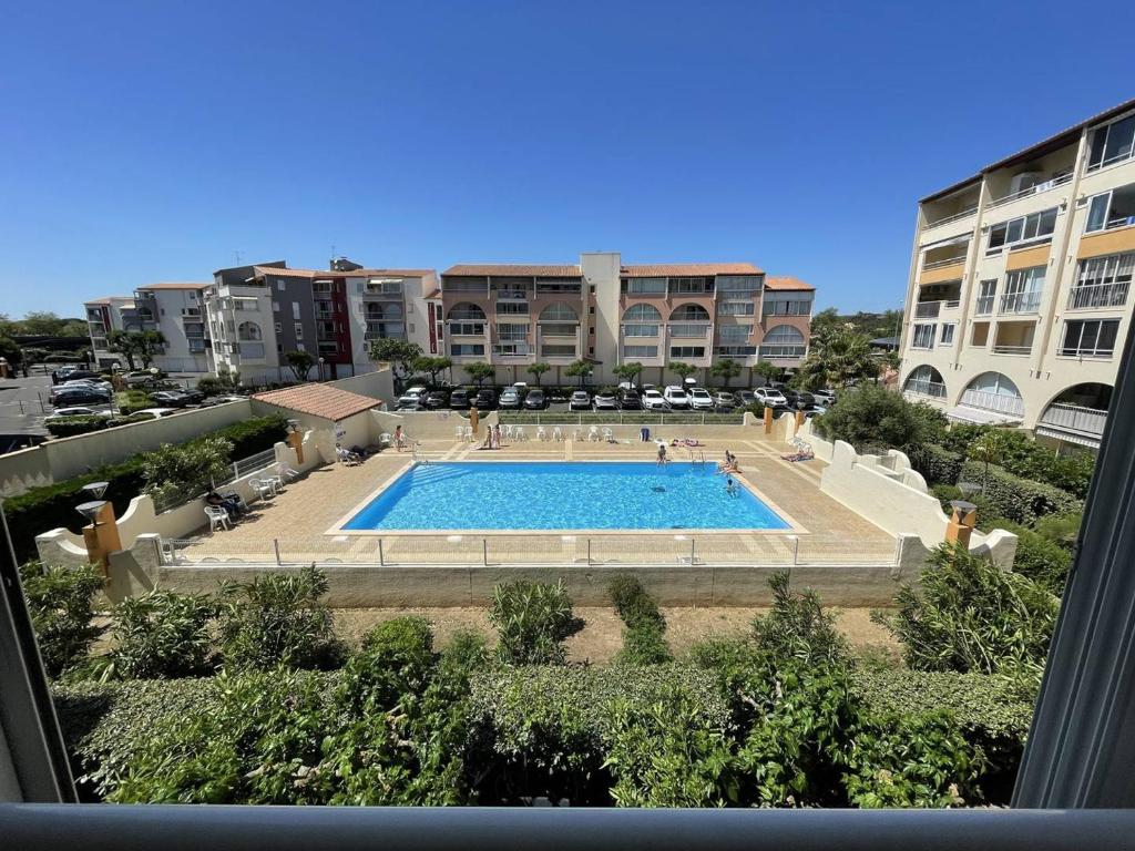 Blick auf den Pool vor einigen Gebäuden in der Unterkunft Appartement Cap d'Agde, 3 pièces, 6 personnes - FR-1-723-54 in Cap d'Agde