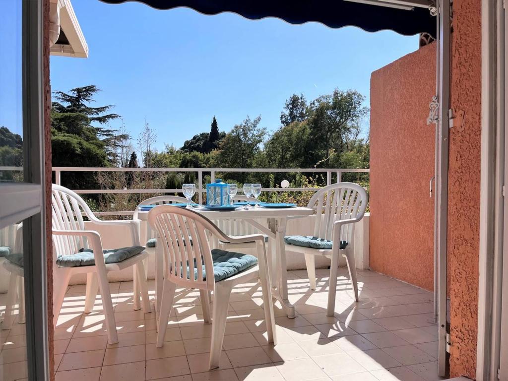 une table blanche et des chaises sur un balcon dans l'établissement Duplex ensoleillé avec terrasse, 5 couchages, proche plage, parking inclus - Le Lavandou - FR-1-251-565, au Lavandou
