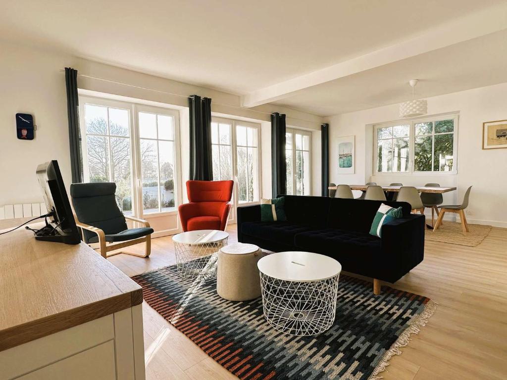 - un salon avec un canapé noir et des chaises dans l'établissement Maison rénovée avec jardin, proche plage Kerleven, 8 pers, Golf Cornouaille à 1.8 km - FR-1-481-153, à La Forêt-Fouesnant