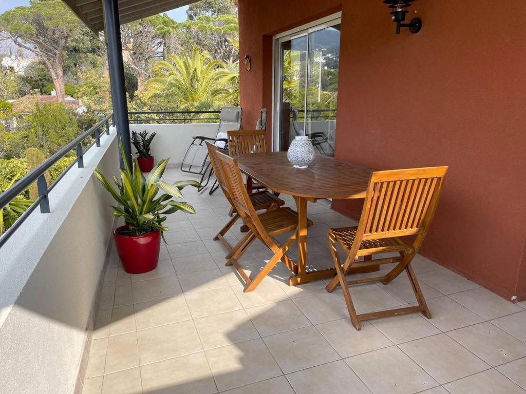 une terrasse couverte avec une table et des chaises en bois sur un balcon dans l'établissement Appartement 2 chambres + mezzanine, proche plage, climatisé, terrasse, parking réservé - FR-1-768-61, aux Issambres