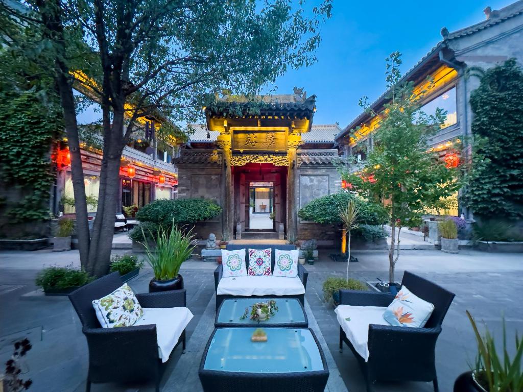 un patio avec des canapés et des tables en face d'un bâtiment dans l'établissement Datong Yunzhong Traditional Courtyard, à Datong