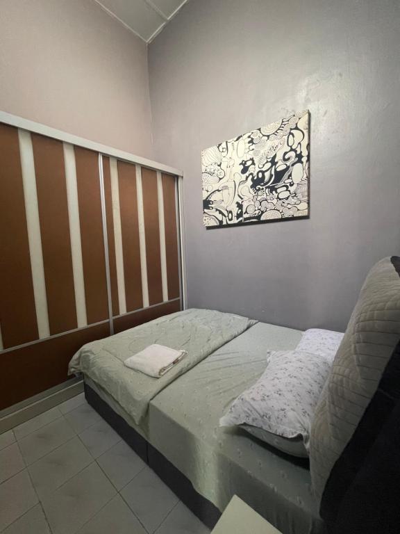 ein Schlafzimmer mit einem Bett und einem Bild an der Wand in der Unterkunft Homestay Permai Inn in Temerloh