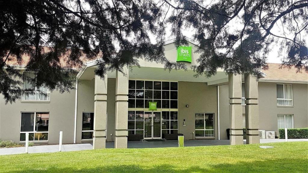 a building with a green sign on the front of it at ibis Styles Canberra in Canberra