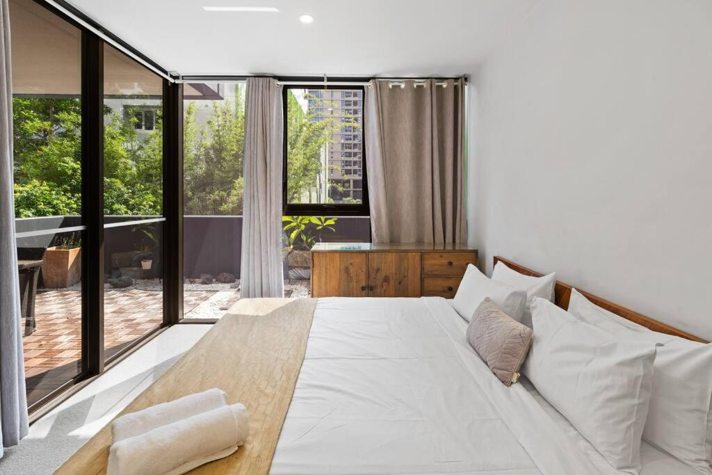 a bedroom with a large white bed and large windows at Southbank One Bedroom Home with Free Parking in Brisbane