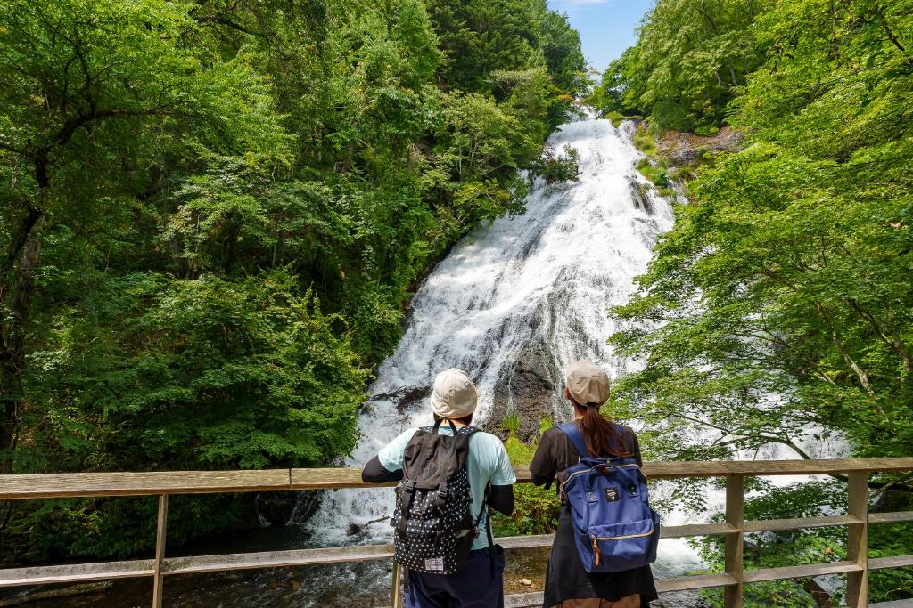 Due persone in piedi di fronte a una cascata di KAMENOI HOTEL Okunikko a Nikko