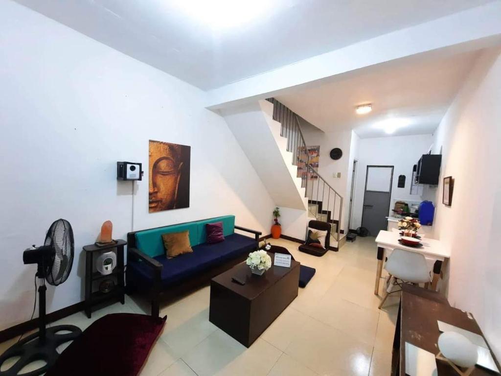 een woonkamer met een blauwe bank en een trap bij 1BR or 2BR Staycation in Quezon City 5 in Manilla