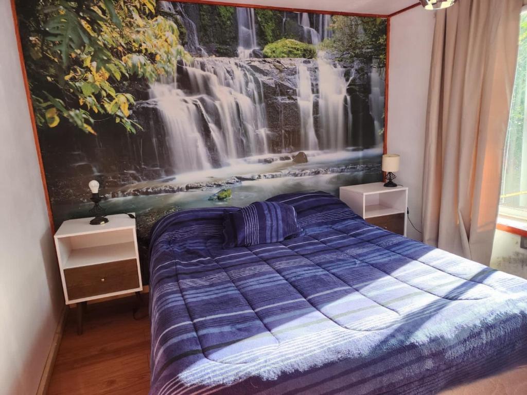 a bedroom with a waterfall mural on the wall at Cabañas Rústicas Pucon in Pucón