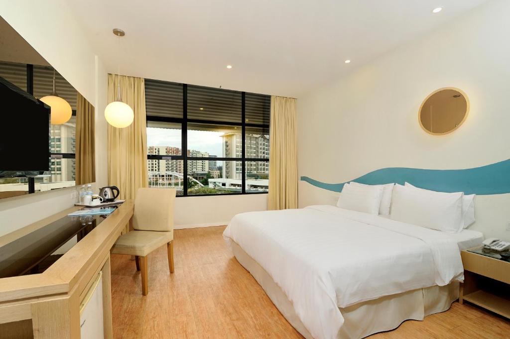 - une chambre avec un lit, un bureau et une télévision dans l'établissement Oceania Hotel, à Kota Kinabalu