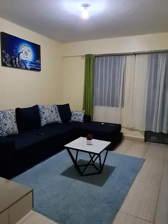 a living room with a black couch and a table at La Ribera Cosy Homes in Bomet