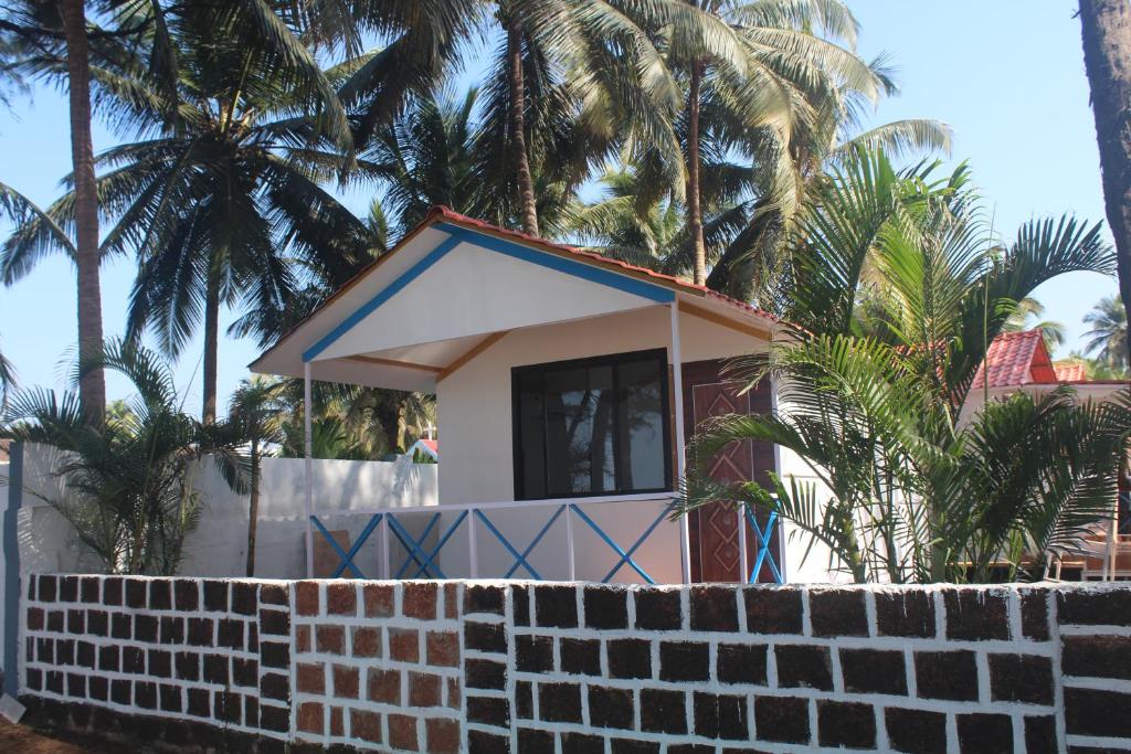 a house on the beach with a brick wall at Nikhil's Beach Cottages in Canacona