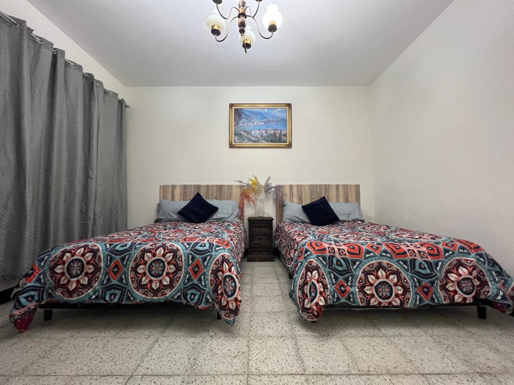 een slaapkamer met 2 bedden en een kroonluchter bij Casa Xibalba in Guatemala