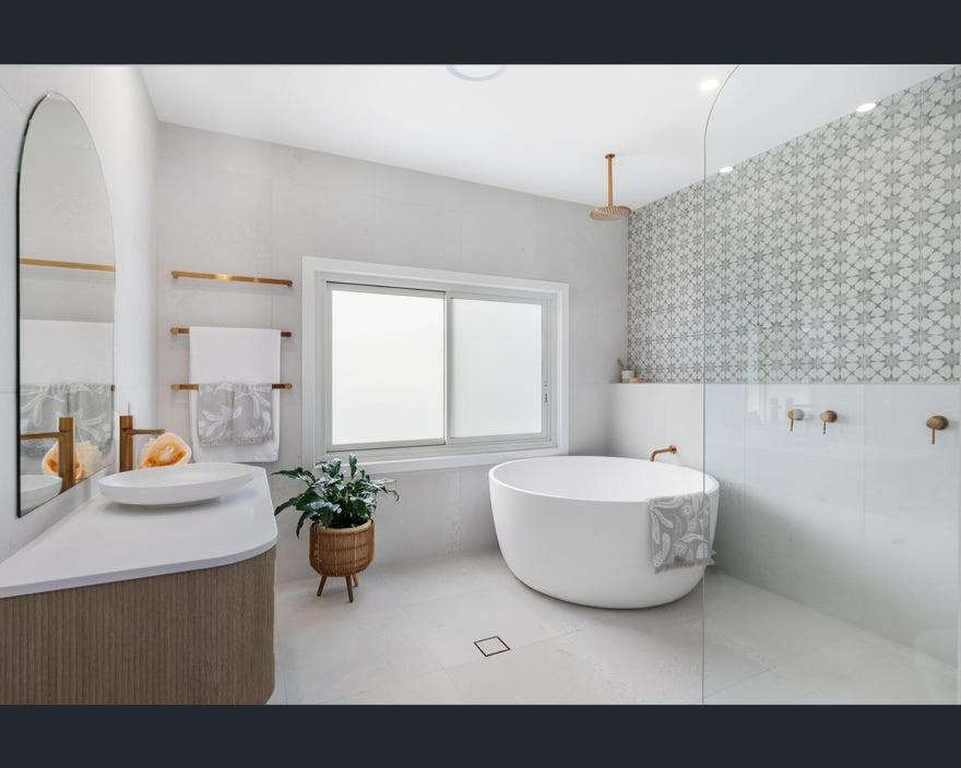 ein weißes Badezimmer mit einer großen Badewanne und einem Waschbecken in der Unterkunft Ocean Lake Oasis in Wamberal