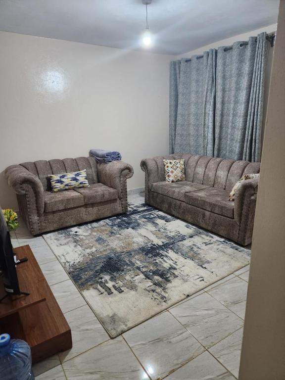 a living room with two couches and a rug at Muthiga Springs Apartment in Kikuyu