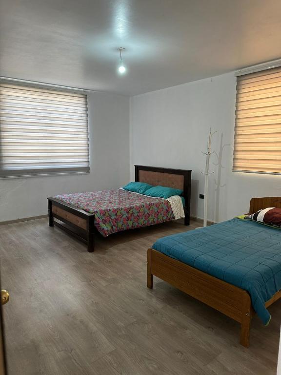 a room with two beds and two windows at Casa cómoda, grande y agradable. in Arica