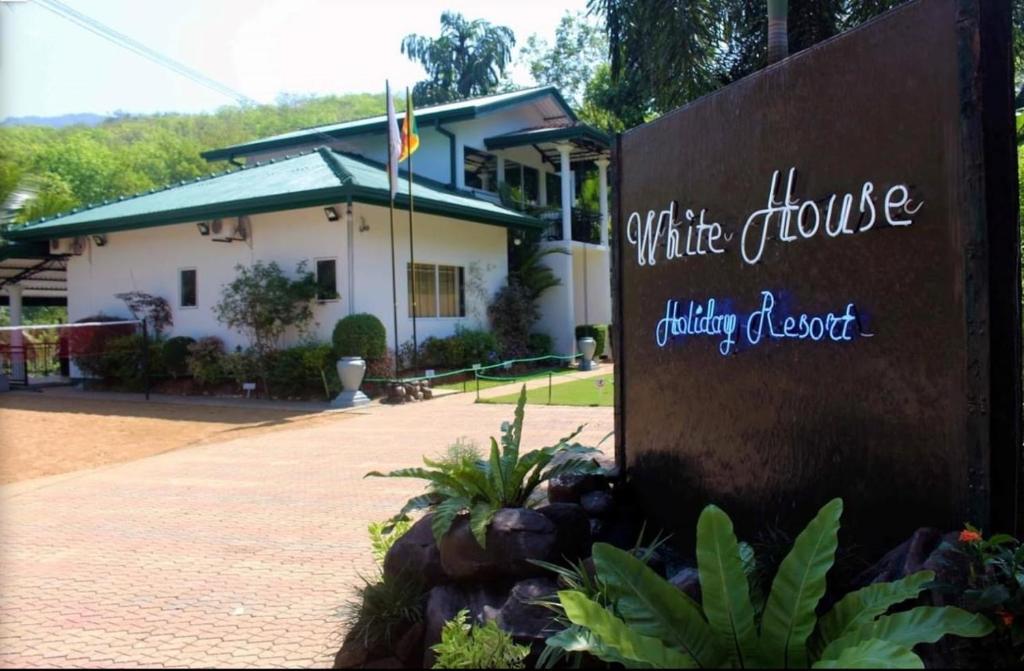 a sign in front of a white house with a building at White House Holiday Resort in Ratnapura