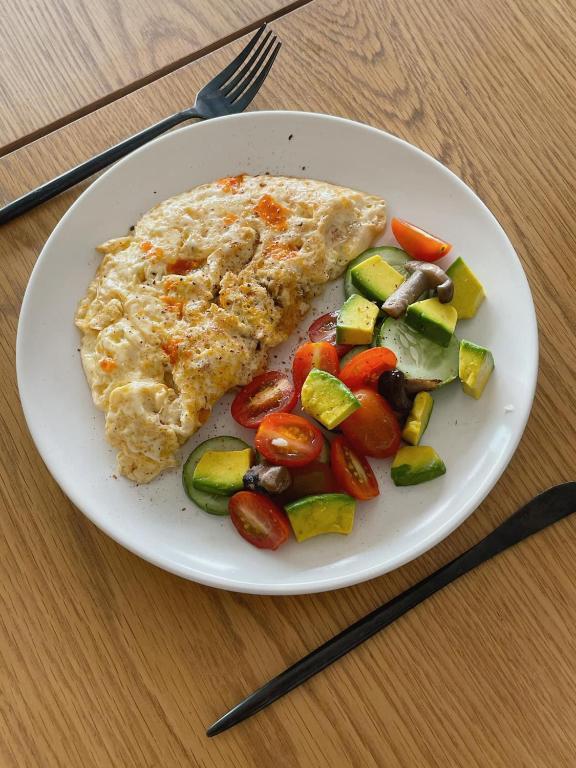 un piatto di cibo con un pezzo di frittata e verdure di Tranquility Stay Old Quarter a Hanoi