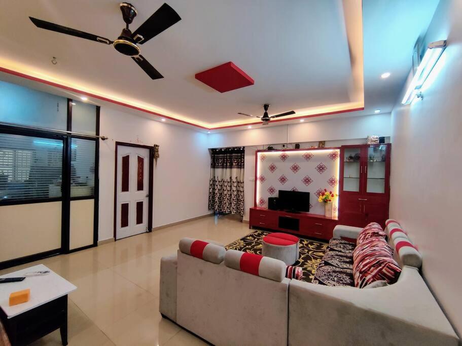 een woonkamer met een bank en een tv bij Luxurious 3 bhk apartment with swimming pool in Bangalore