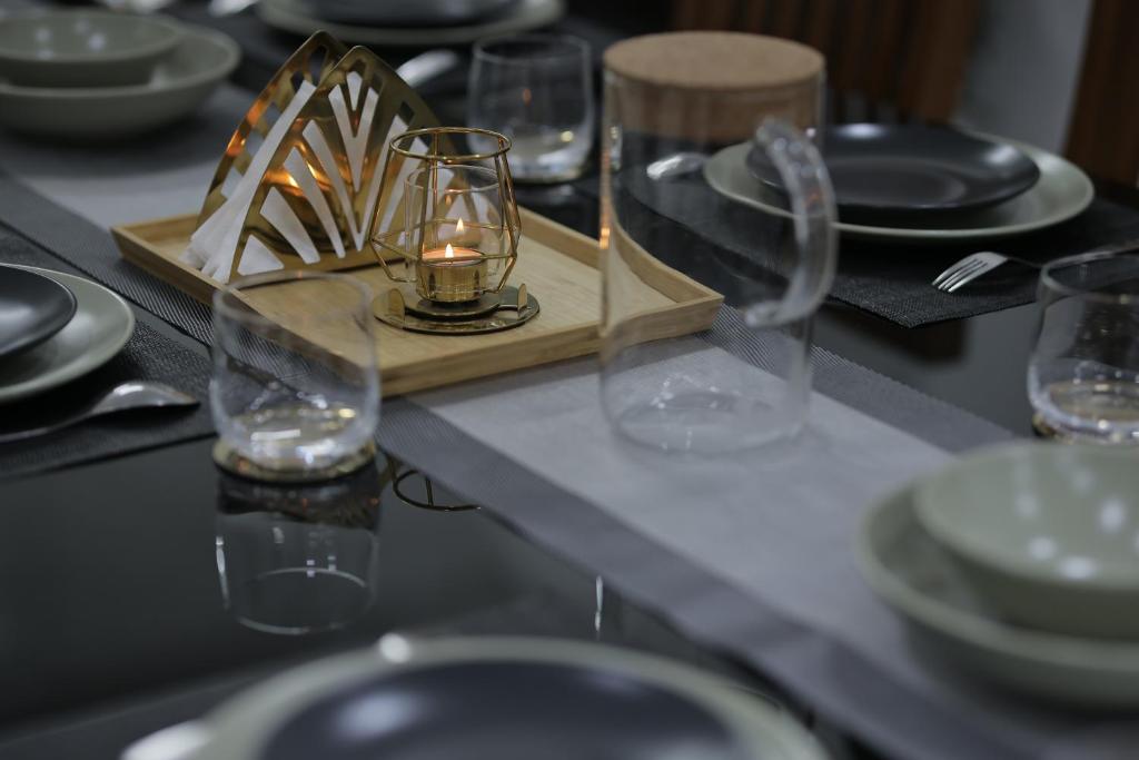 una mesa con platos y vasos y una vela en ella en INDIGO PALMS en Thiruvananthapuram
