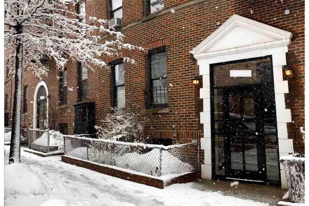 een met sneeuw bedekt gebouw met een deur ervoor bij SUNNYside one bedroom apt in Woodside