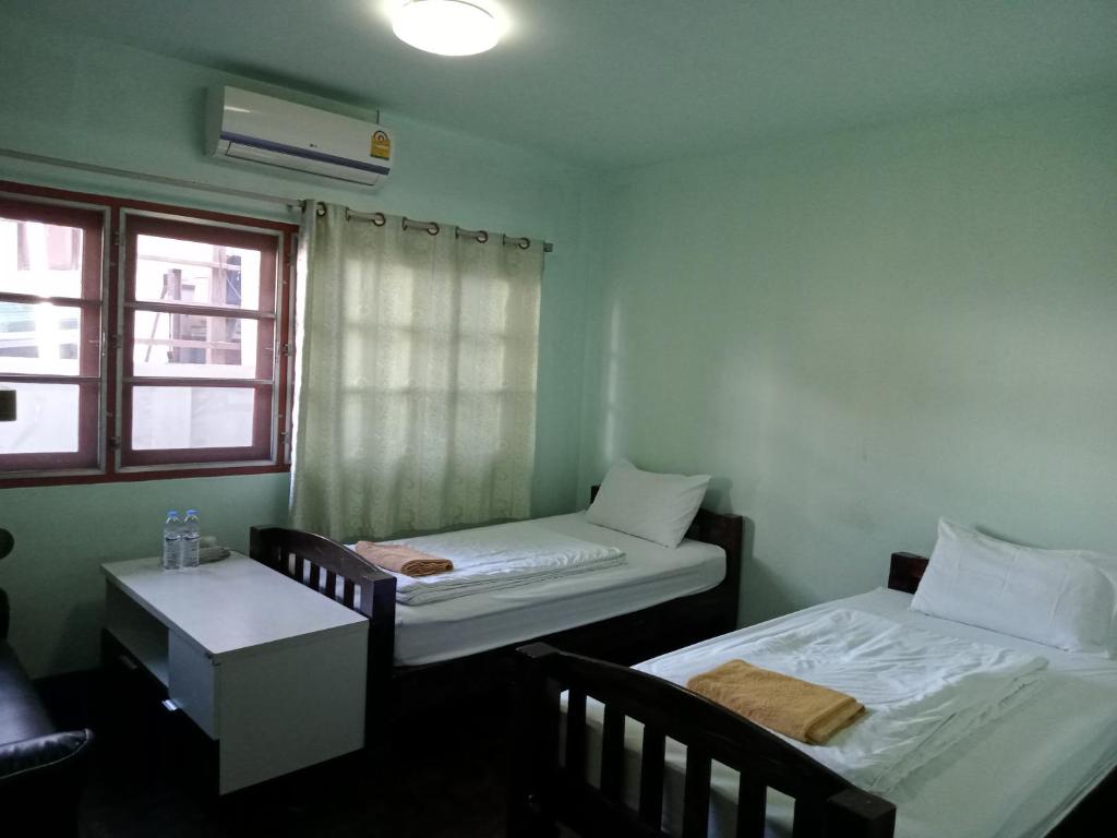 Habitación con 2 camas, mesa y ventana en Sakura House en Chiang Mai