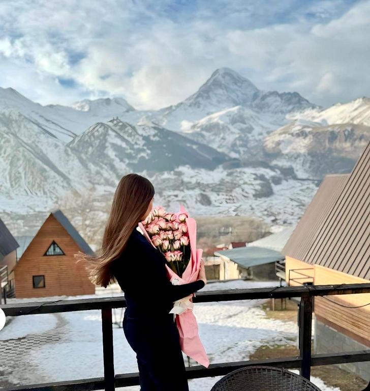 Una donna che tiene un bambino in cima a una montagna di Guesthouse Elli & Cottages a Kazbegi