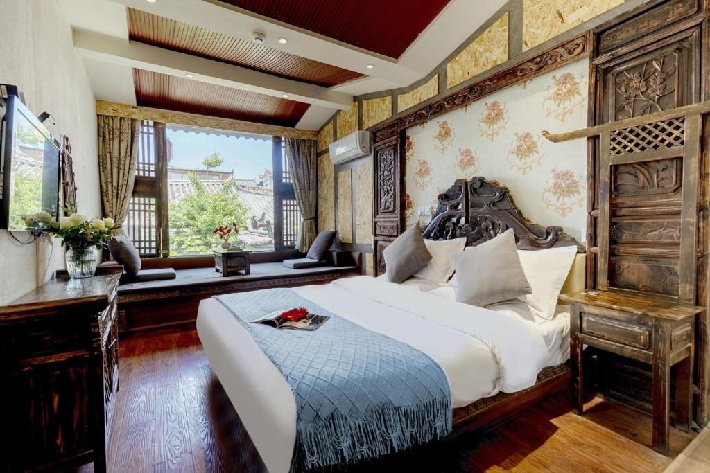 sypialnia z dużym łóżkiem z drewnianym zagłówkiem w obiekcie RUI XIANG HE INN - Lijiang Ancient Town w mieście Lijiang