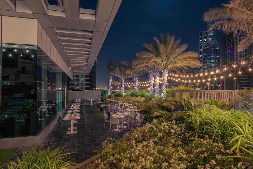 a restaurant at night with lights and palm trees at Stella Di Mare Dubai Marina Hotel in Dubai
