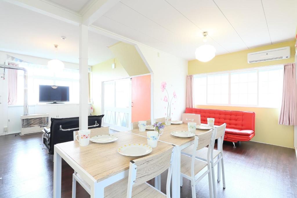 ein Esszimmer mit einem Tisch und einem roten Sofa in der Unterkunft Sungarden - Vacation STAY 95967 in Otaru