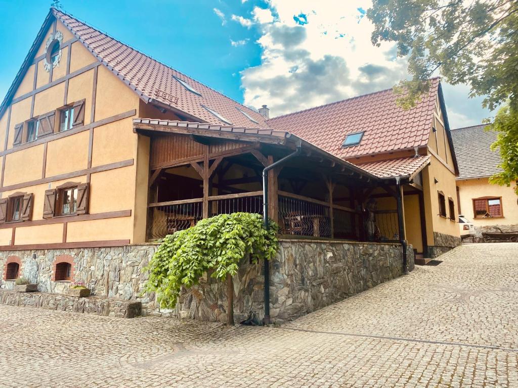 a large building with a stone wall in front of it at Agroturystyka Agro-Podkówka in Marciszów