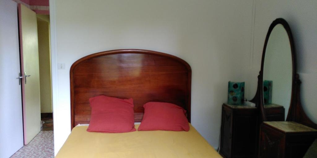 a bed with a wooden headboard and two red pillows at Villa Lulu in Mérignac