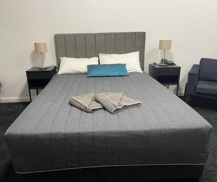 a bed with two towels on it with two lamps at City West Motel in Adelaide