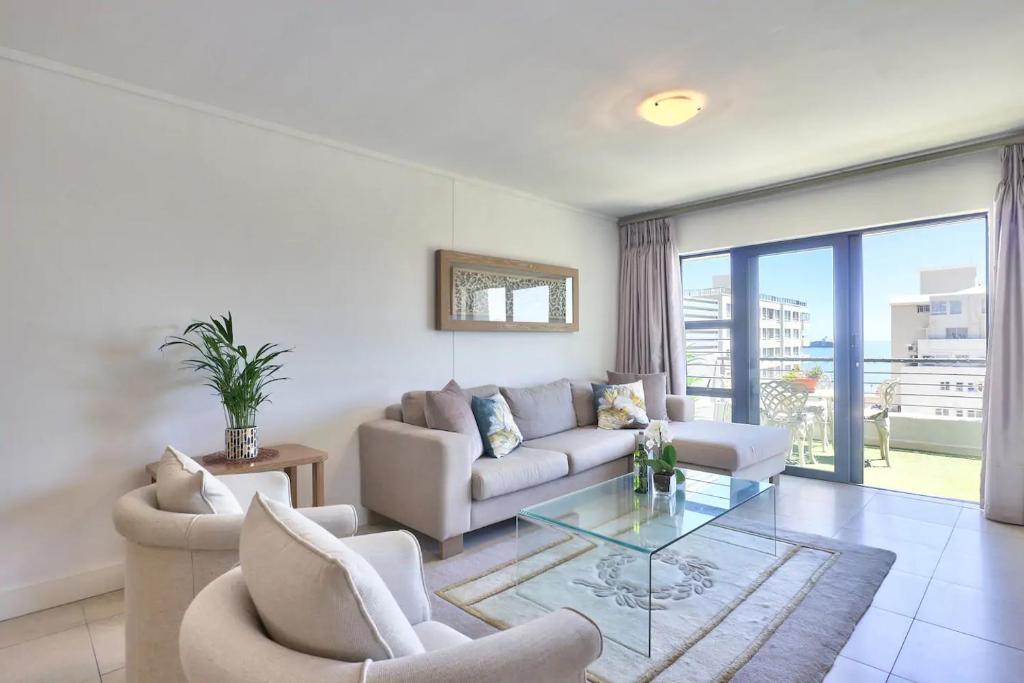 sala de estar con sofá y mesa de cristal en Stylish sea-facing apartment with underground parking, en Ciudad del Cabo