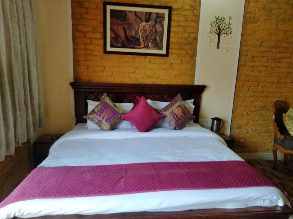 1 dormitorio con 1 cama grande con almohadas rosas en Kesaria Tiger Huts, en Khilchīpur