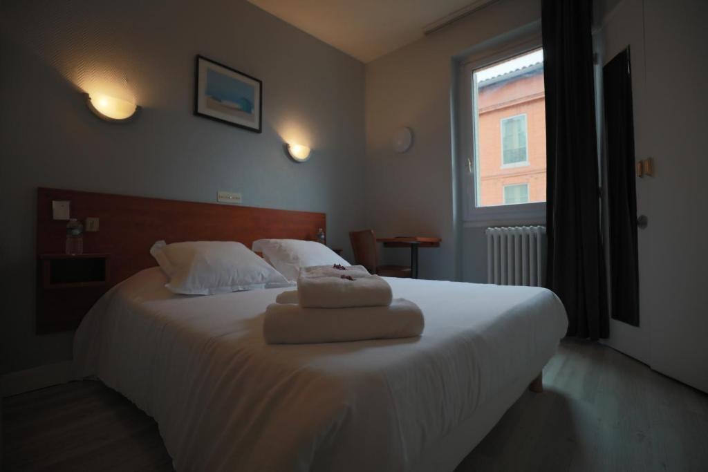 a bedroom with a bed with two towels on it at Hotel Wilson Square in Toulouse