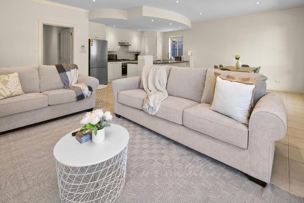 a living room with two couches and a table at Beaumont Bliss: 4BR 2 5BA Family Retreat in Glenunga