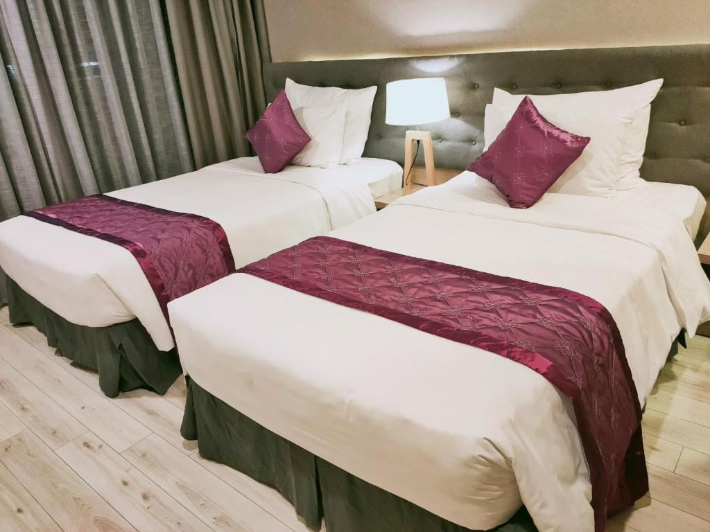 2 łóżka w pokoju hotelowym z fioletowymi poduszkami w obiekcie Resort Oceanami Vũng Tàu w mieście Long Hai