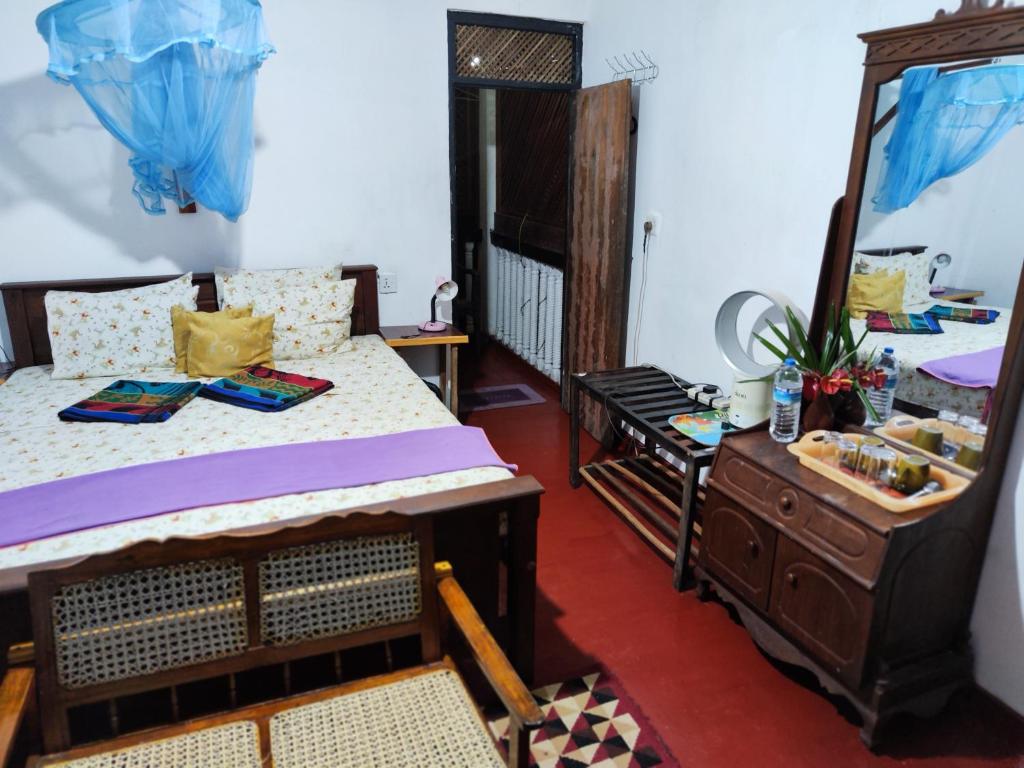 um quarto com uma cama, uma cómoda e um espelho em AnandaHomestay em Kandy