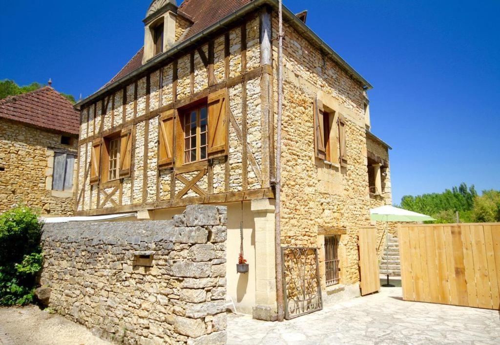 un antiguo edificio de piedra con ventanas y una valla en La Maion, en Daglan