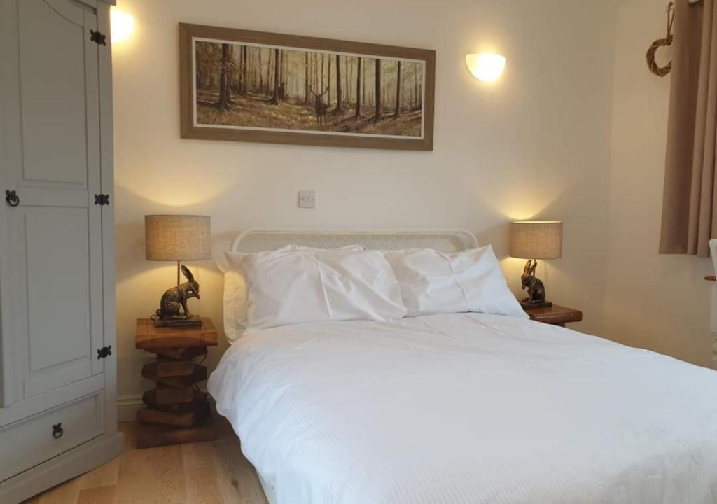 a bedroom with a large white bed with two lamps at Cobble View Cottage in Waddington